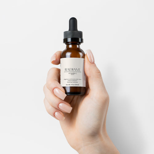 Hand holding a bottle of Radiave skincare serum against a light background